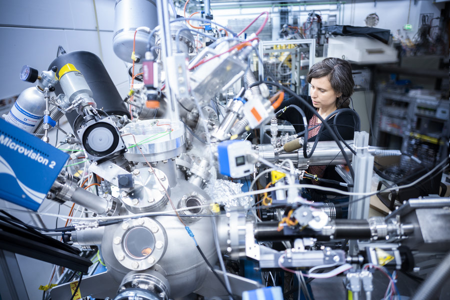 Materialforschung Eine Frau beugt sich über einen silbernen Experimentaufbau.