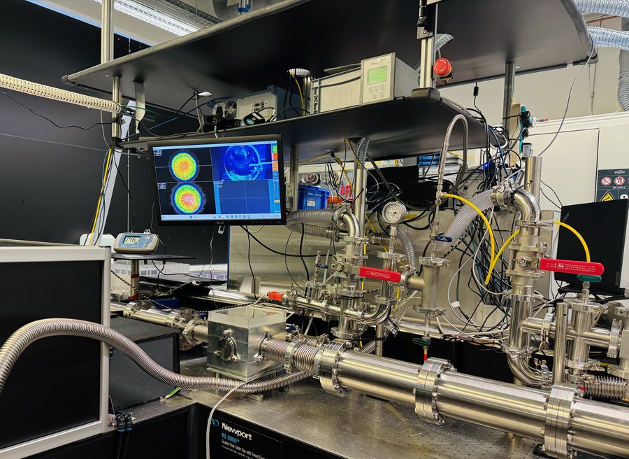 High power multipass cell for spectral broadening of Yb-fiber lasers Ein komplexer Messaufbau aus silbernen Rohren, Kabeln und einem Monitor steht auf einem Tisch.