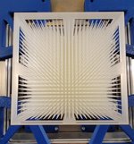 Modulator In einem blauen Metallrahmen ist ein weißes, rechteckiges Objekt mit vielen nach vorn ragenden Spitzen montiert.