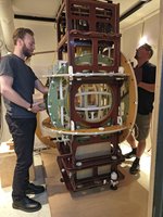 Experimentaufbau in Berlin Zwei Männer stehen rechts und links von einem überkopfhohen, verschachtelten Holzgerüst.