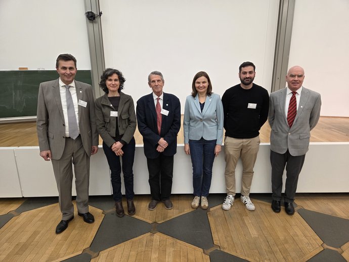 Four men and two women stand in front of a stage. Four men and two women stand in front of a stage.