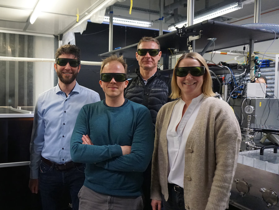 Lab tour Vier Personen mit Laserschutzbrillen stehen vor einen Experimentaufbau.