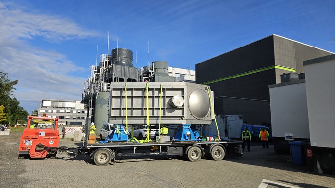 Eine große, silberne Metallkammer steht auf einem Transportanhänger. Eine große, silberne Metallkammer steht auf einem Transportanhänger.