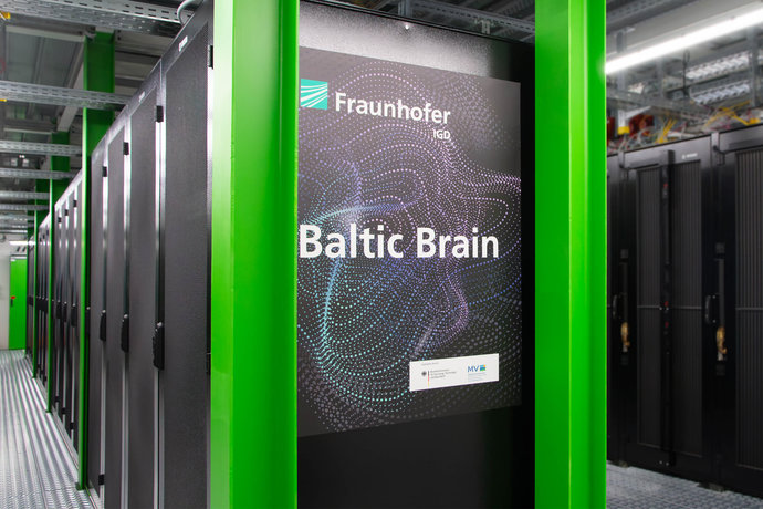 Eine Reihe von schwarzen Rechnerschränken ist in einem Gerüst von grünen Metallträgern aufgestellt. Am Kopfende prangt ein Aufkleber mit der Aufschrift "Baltic Brain". Eine Reihe von schwarzen Rechnerschränken ist in einem Gerüst von grünen Metallträgern aufgestellt. Am Kopfende prangt ein Aufkleber mit der Aufschrift "Baltic Brain".